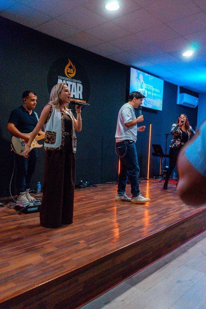 El equipo de alabanza cantando sobre la tarima, con guitarra y tres voces