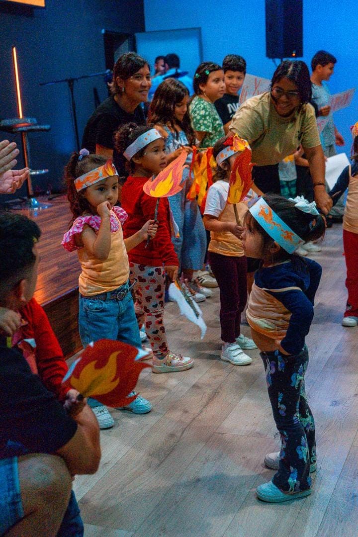 Los niños del ministerio infantil con diademas y antorchas de papel, acompañados por sus monitoras