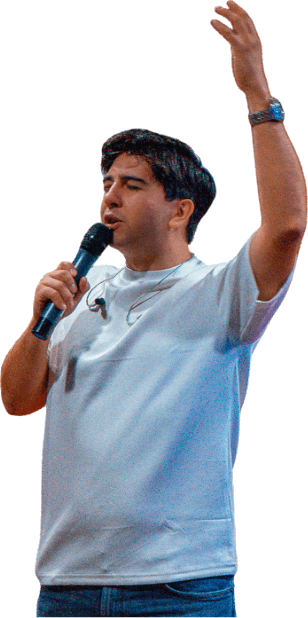 El pastor Ismael Llanes cantando con un micrófono y el brazo levantado